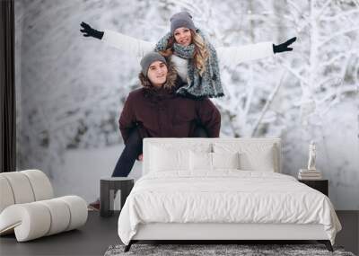 Embracing couple looking at camera with smiles in winter park Wall mural