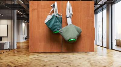 Two green respirator masks hang on a nail driven into wooden boards on the wall. Protecting lungs and health from inhaling harmful chemicals and poisons. Wall mural