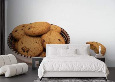 Oatmeal cookies with chocolate chips lie in a painted earthenware bowl, two halves lie next to Wall mural