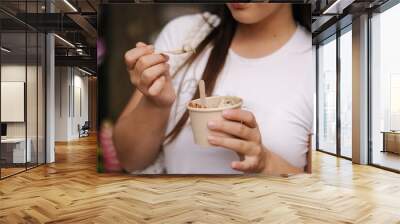 Portrait of attractive woman eating ice cream outdoors. Rest after shopping Wall mural