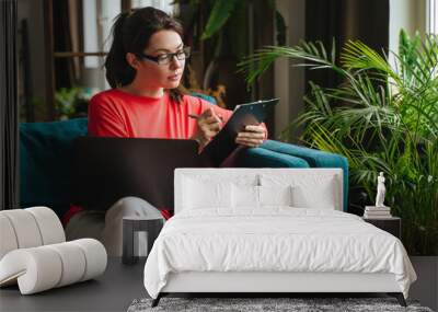 Businesswoman typing an e-mail on laptop at home office. Wall mural