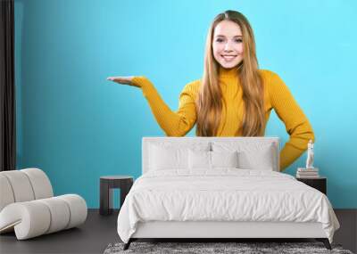 Portrait cheerful pretty young lady standing isolated over blue background. Looking camera showing copyspace Wall mural