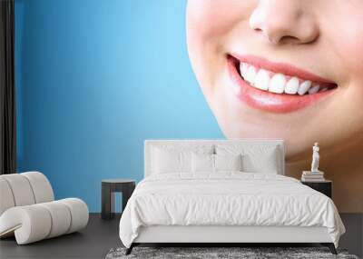 Stomatology concept. Partial portrait of a girl with white teeth smiling. Closeup of young woman at dentist's, studio, indoors. isolated on blue background. Wall mural