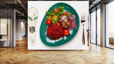 Beef steak with a side dish of carrots, beets and tomatoes on a green plate Wall mural