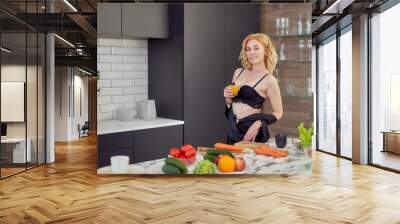 young woman in peignoir with a glass of orange juice in her hand in a vegan kitchen Wall mural