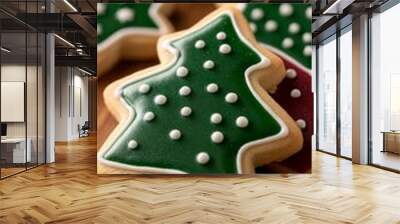 Christmas cookies shaped like stars and trees covered in colorful icing placed on a wooden table with pine branches festive and delicious warm and cozy atmosphere red and green palette Wall mural