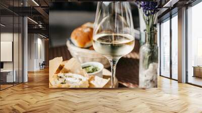 Glass of cold white wine and oven baked camembert cheese with rosemary on baking paper on wooden plate. Serving lunch at the winery, rustic style table setting Wall mural