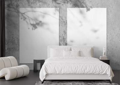 Two empty white vertical rectangle poster or card mockups with soft tree leaves and branches shadows on neutral light grey concrete wall background. Flat lay, top view Wall mural