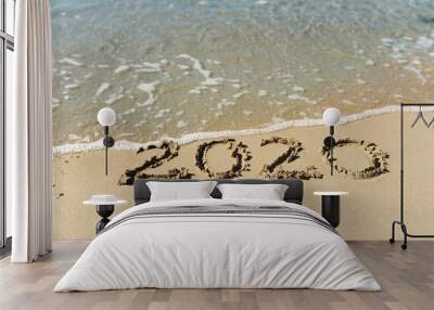 wave of clear blue clear sea water washes away the inscription on the sand 2020, selective focus Wall mural