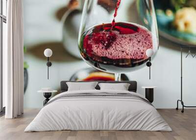 Selective focus shot of pouring red wine into the glass on a white table, dinner table at restaurant Wall mural