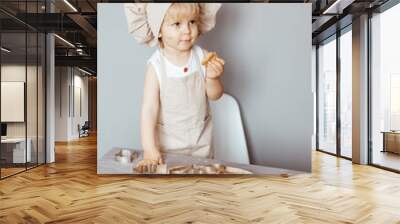 a happy child in an apron and a chef's hat prepares dough Wall mural