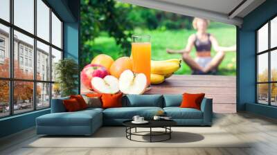 Lifestyle, sport and healthcare. A woman during yoga exercises outdoor. Healthy food on the table Wall mural