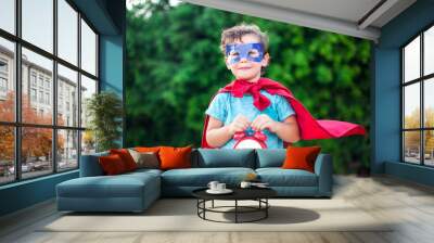 Superhero kid with alarm clock against green background outdoor. Childhood, success and and power concept Wall mural