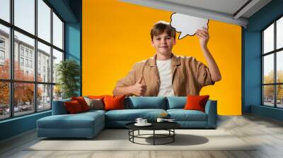 Teen boy holding think cloud bubble card and pointing finger up. Dreaming and idea concept Wall mural