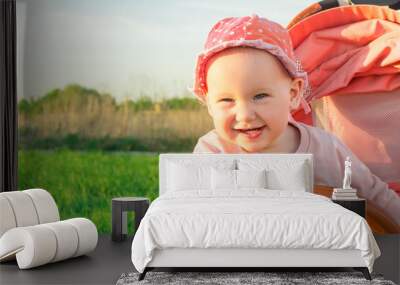 Little baby girl sitting in a stroller and smiling cute. Wall mural