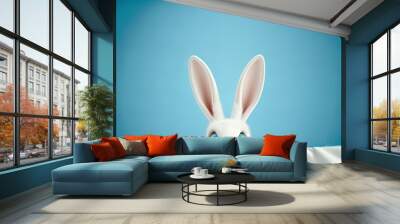 Cute easter rabbit sticking out green grass corner on blue sky background with empty space for text or product. Currious small bunny symbol of spring and easter Wall mural