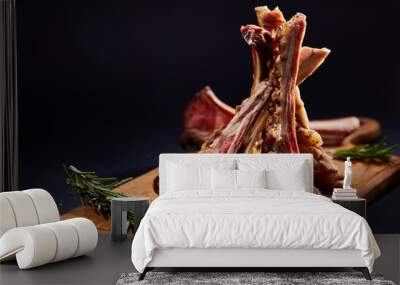 Rack of lamb with rosemary on wooden cutting board over dark background, side view, selective focus Wall mural