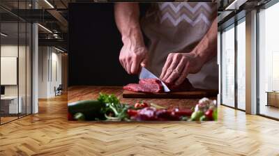 Strong professional man's hands cutting raw beefsteak, selective focus, close-up Wall mural