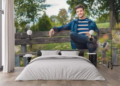 Positive young man with smile on his face sitting on bench Wall mural