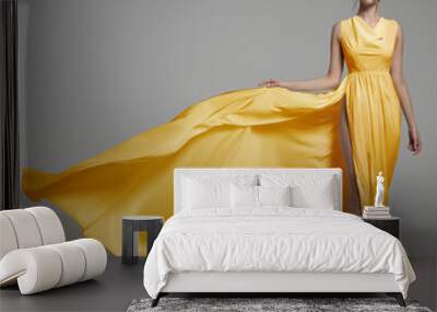 Fashion woman in long silk yellow dress. Gray background Wall mural