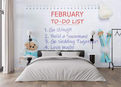 February to-do list. Notepad with to-do list and a toy Teddy bear in blue clothes, blue skis, a white hat on white snow Wall mural