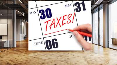 Hand drawing red line and writing the text Taxes on calendar date May 30. Remind date of tax payment Wall mural