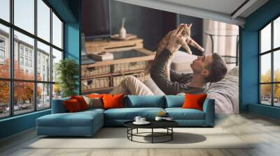 Handsome teenage guy relaxing on modern soft couch at home in living room Wall mural