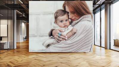 Mom and baby dressed in warm winter knitted clothing Wall mural