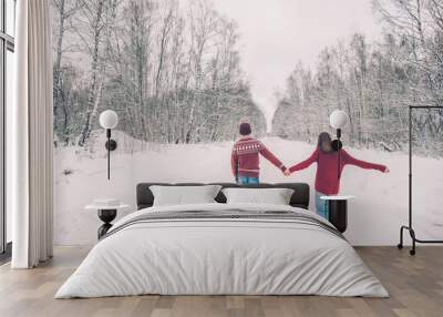 Teenagers in Christmas sweaters walking in snow in winter Wall mural