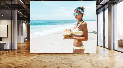 Woman drinking coconut on the tropical beach Wall mural