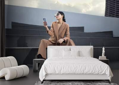 Portrait of a successful business woman sitting on stairs. the phone is in her hands. City background Wall mural