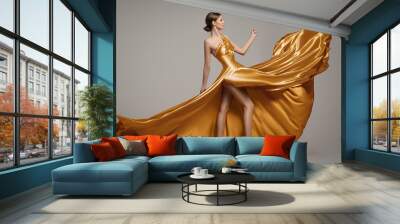 Slim fashion woman with long gold dress. Gray background Wall mural