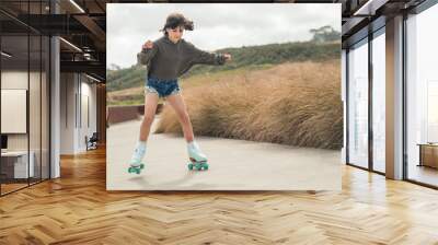 portrait of young child or teen girl roller skating outdoors, firness, wellbeing, active healthy lifestyle Wall mural