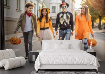 Young people in costumes celebrating halloween. Group of teenagers walking down the street on Halloween Wall mural