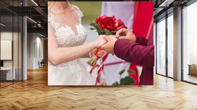 The groom puts anengagement ring on the brides finger on a green backg Wall mural