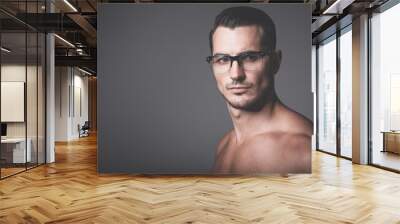 Male beauty concept. Portrait of handsome young man with stylish haircut in glasses posing over gray background. Perfect hair & skin. Close up. Studio shot Wall mural