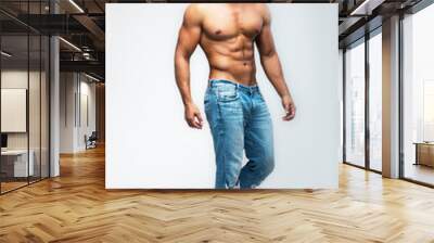 Male model with perfect body in jeans posing over grey background. Close-up. Studio shot. Wall mural