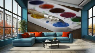 Paintbrush with blue paint lies on box with watercolor paints Wall mural