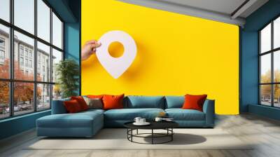 3D location symbol in hand over yellow background, panoramic image Wall mural