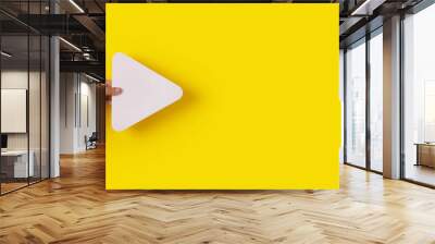 hand holding media player button icon over trendy yellow background, panoramic layout Wall mural