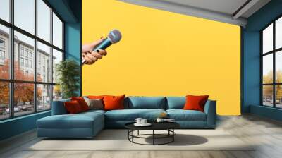 hand holding microphone over yellow background, panoramic mock up image Wall mural