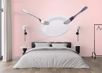 levitating empty plate with knife and fork over pink background, clean kitchenware concept Wall mural