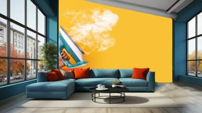 modern iron with steam in hand over yellow background, panoramic mock-up image Wall mural