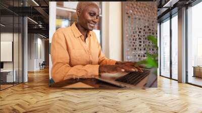 African woman working on laptop in bar restaurant - Afro female typing on computer - Digital nomad and freelance lifestyle concept Wall mural