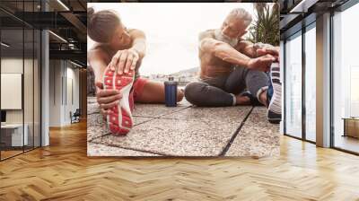 Fitness couple doing stretching exercise outdoor - Happy athletes making workout session at sunset outside - Concept of health mature people training and bodybuilding lifestyle Wall mural