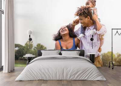 Happy African family enjoying together in public park - Mother, father and daughter having fun during a weekend sunny day outdoor - Happiness, love and parenthood concept Wall mural