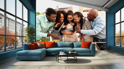 Happy African family preparing food recipe together on house patio Wall mural