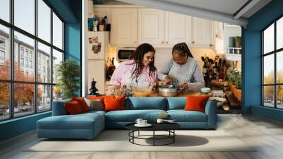 Happy African mother and daughter having fun preparing a homemade dessert Wall mural