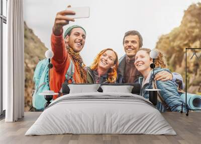 Happy friends taking photo selfie with mobile smartphone camera on mountains - Group young people trekking and having fun with new technology trends - Sport, hiking, Tech and social media concept Wall mural