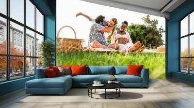 Happy multiracial family having fun together while doing picnic in the park Wall mural